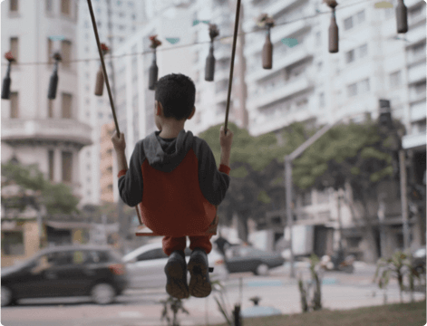 Boy sitting on the swing in an urban center